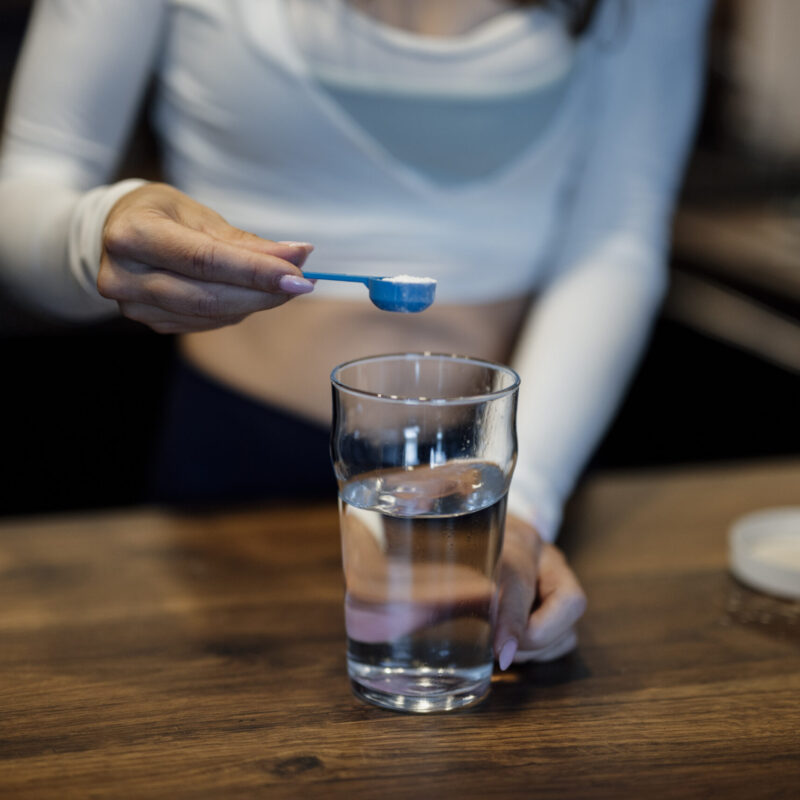 Persona versa una polvere in un bicchiere d'acqua sul bancone della cucina