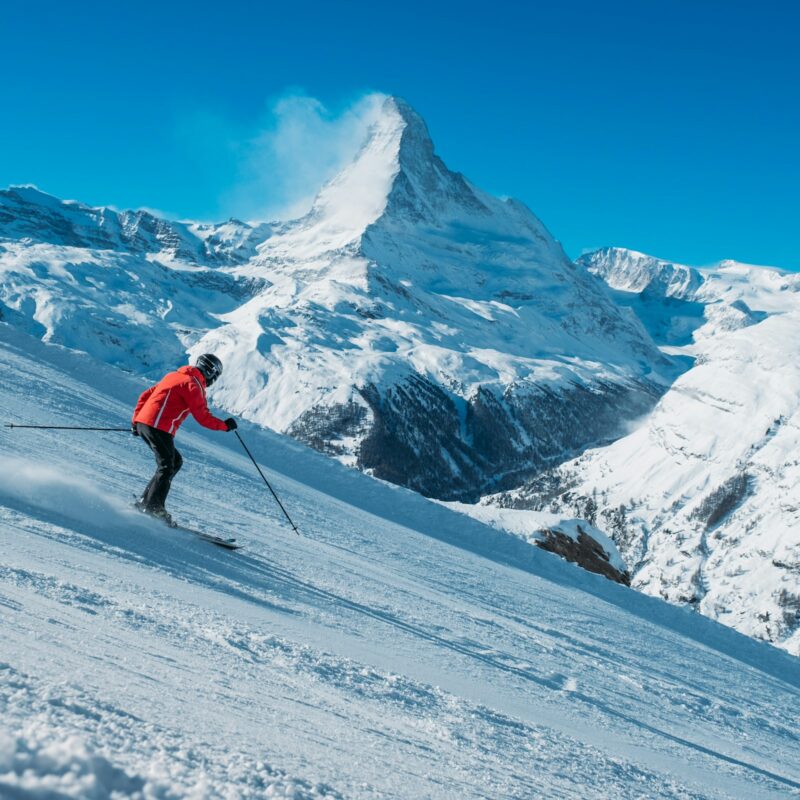 Sciatore in discesa su pista innevata durante una settimana bianca in montagna