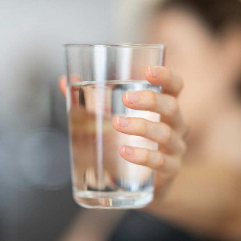 Persona che tiene un bicchiere d'acqua trasparente