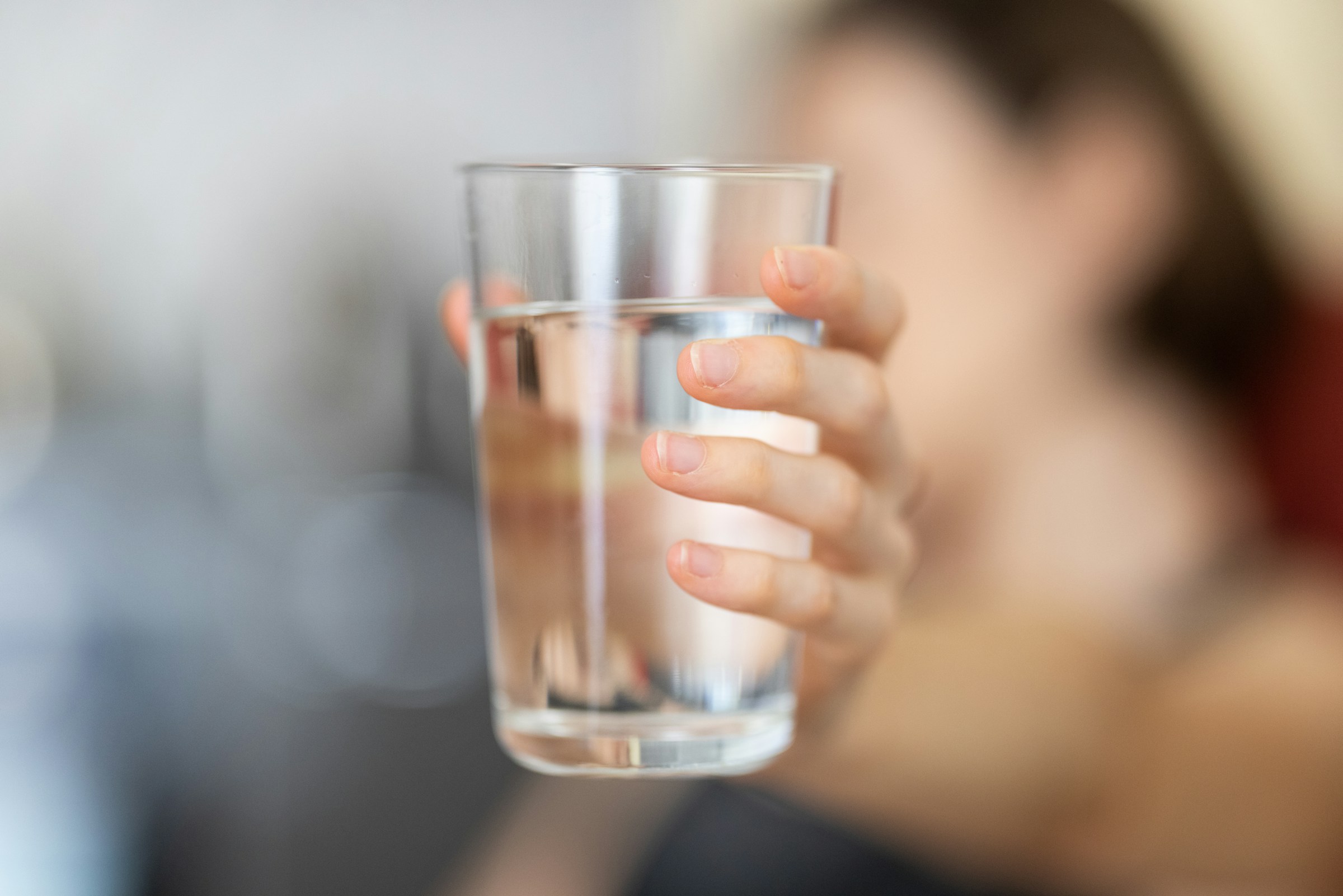 Persona che tiene un bicchiere d'acqua trasparente
