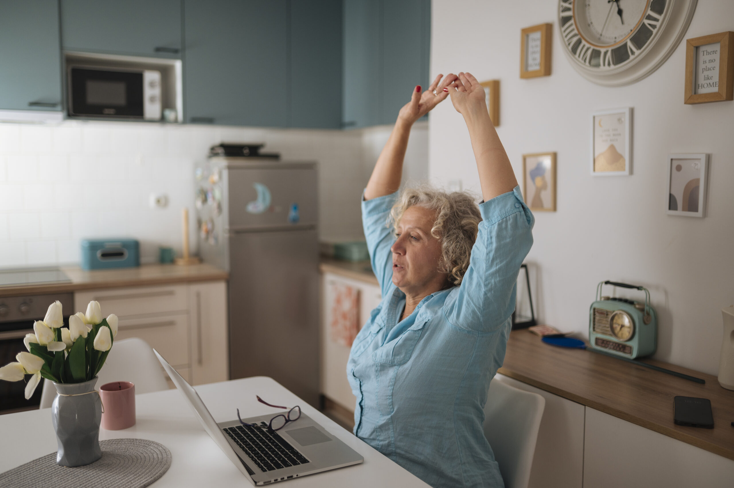 Donna che si stira alla scrivania mentre lavora al computer