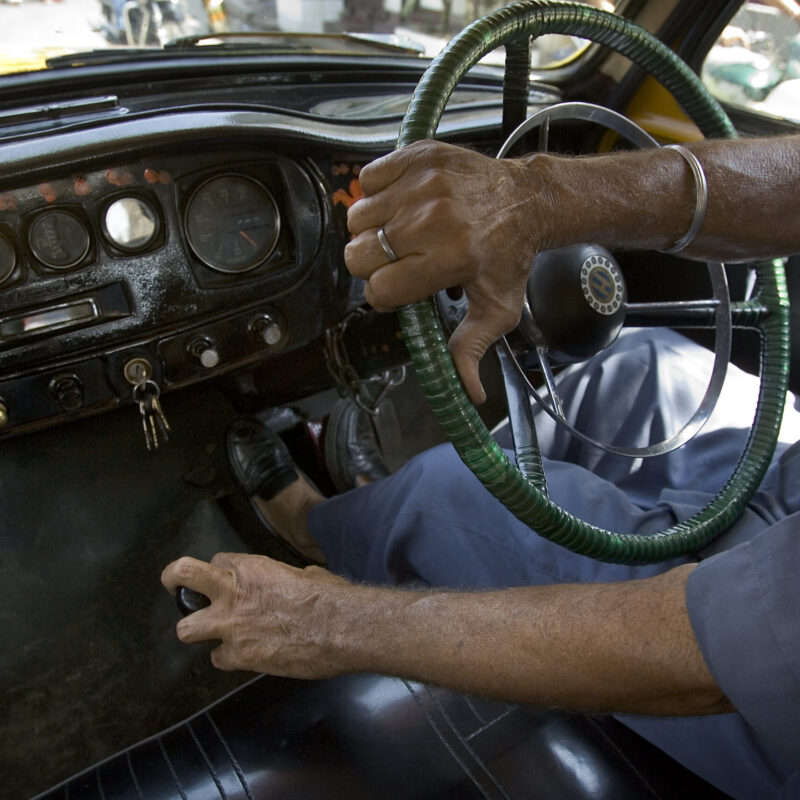 Mano sul volante di un'auto durante la guida in città, vista dall'abitacolo