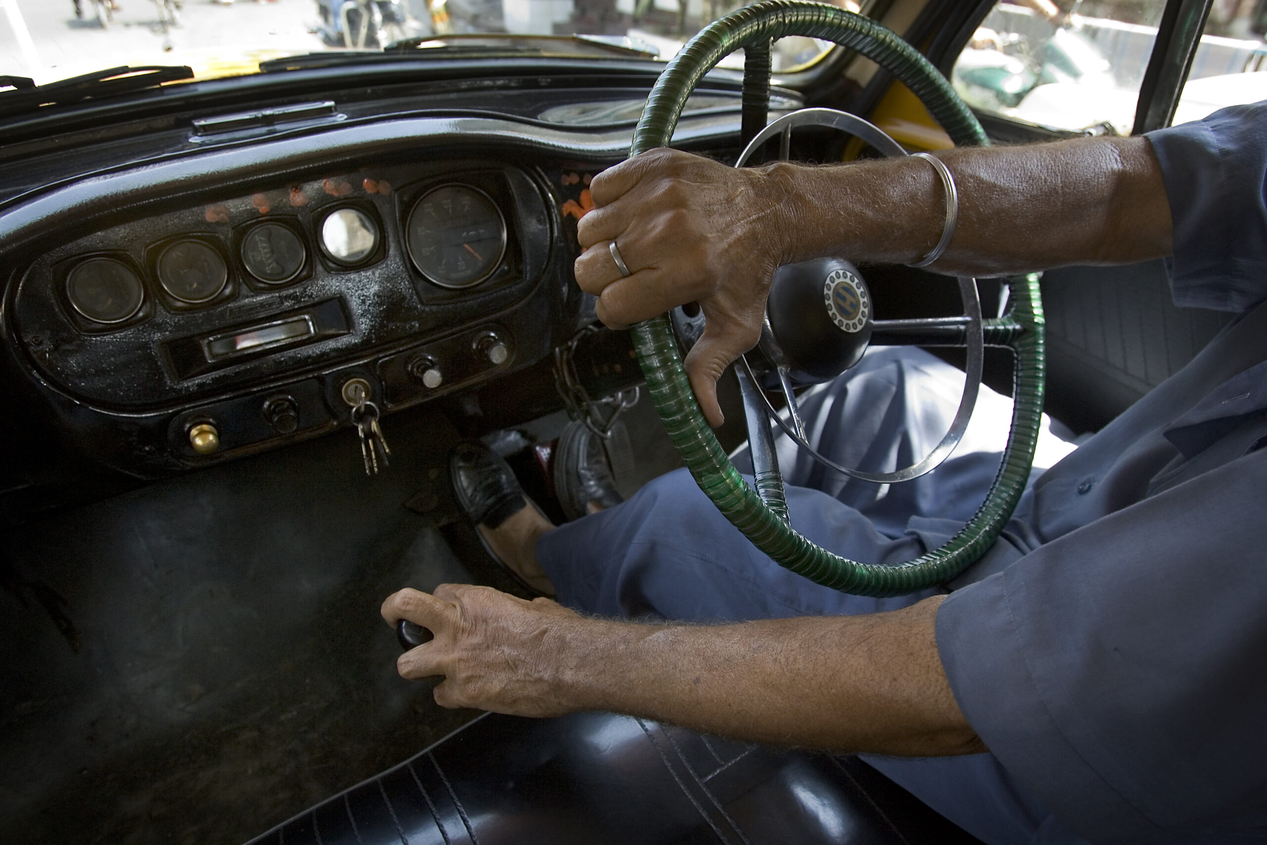 Mano sul volante di un'auto durante la guida in città, vista dall'abitacolo