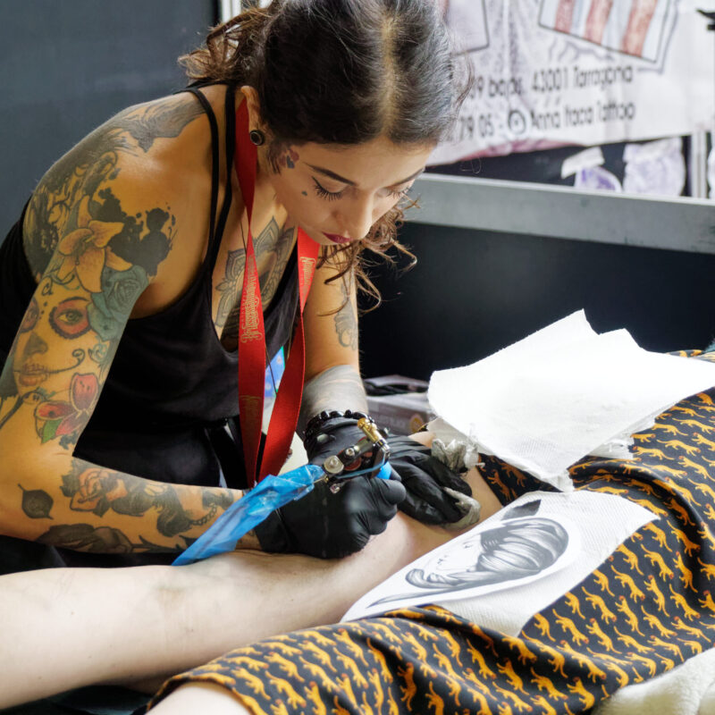 Tatuatrice professionista al lavoro su un tatuaggio durante una convention