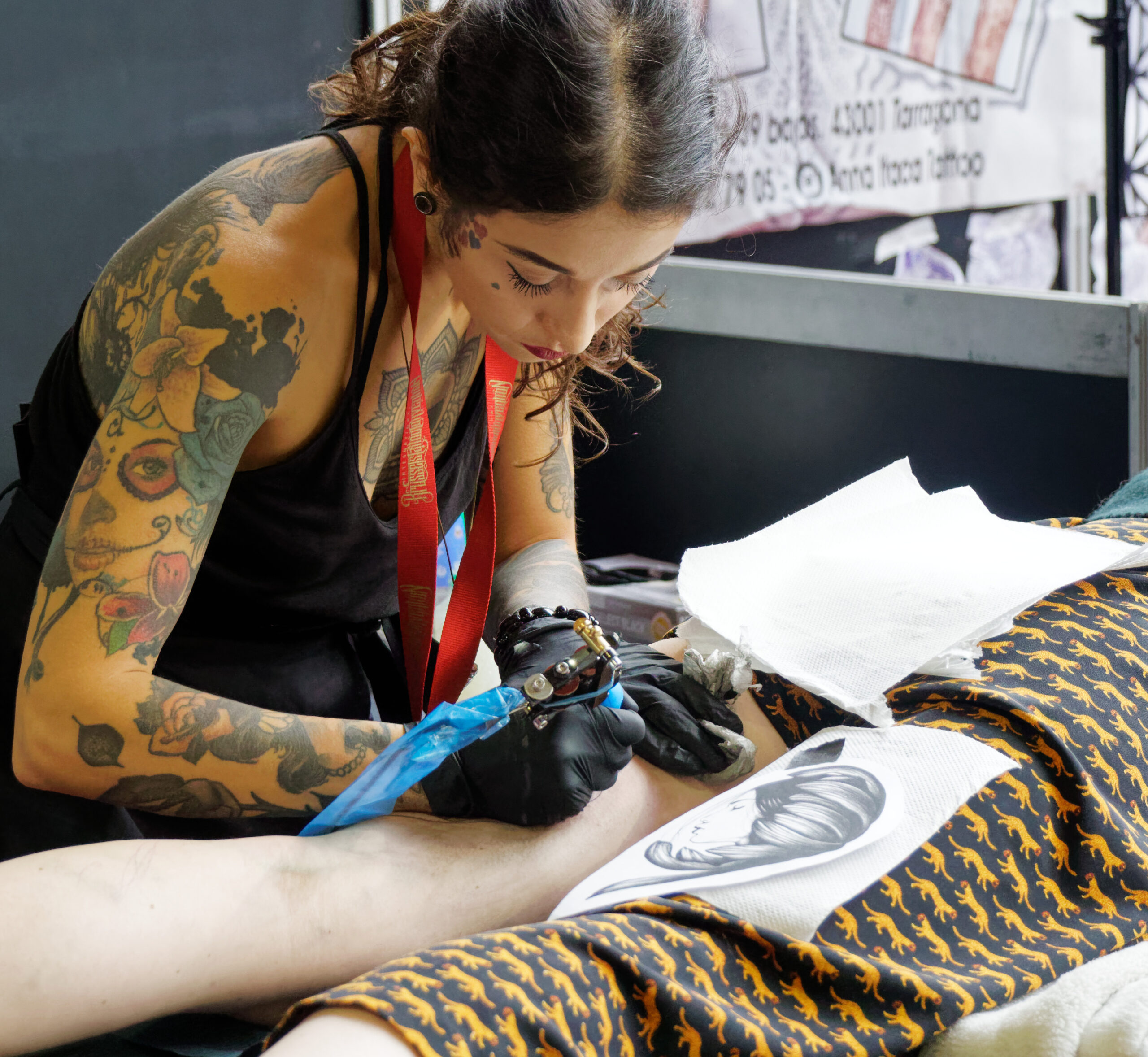Tatuatrice professionista al lavoro su un tatuaggio durante una convention