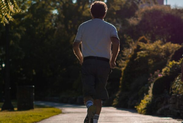 Uomo di spalle mentre corre su un sentiero nel parco in una giornata di sole