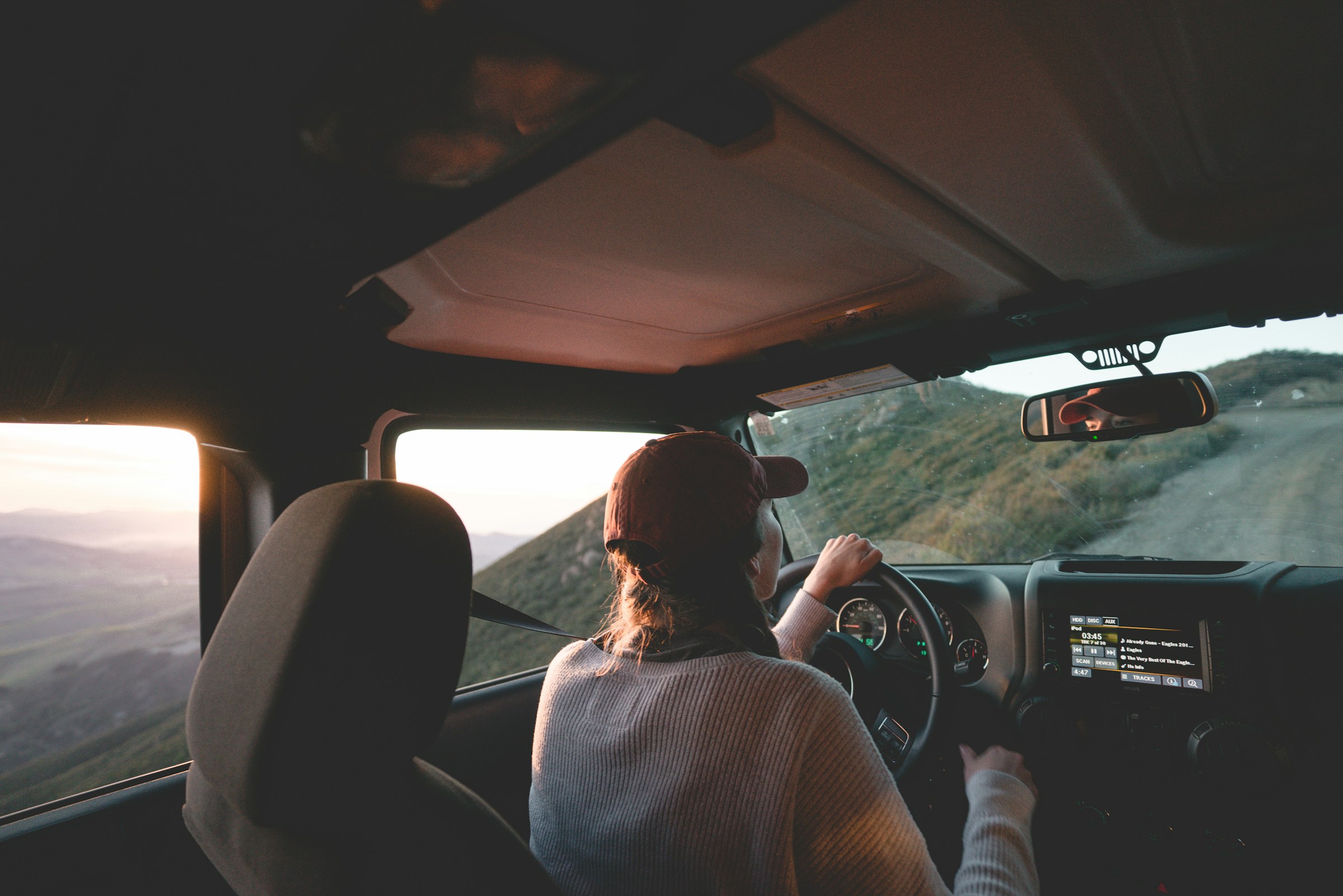 Donna alla guida durante un lungo viaggio in auto in estate, con attenzione a vista e benessere