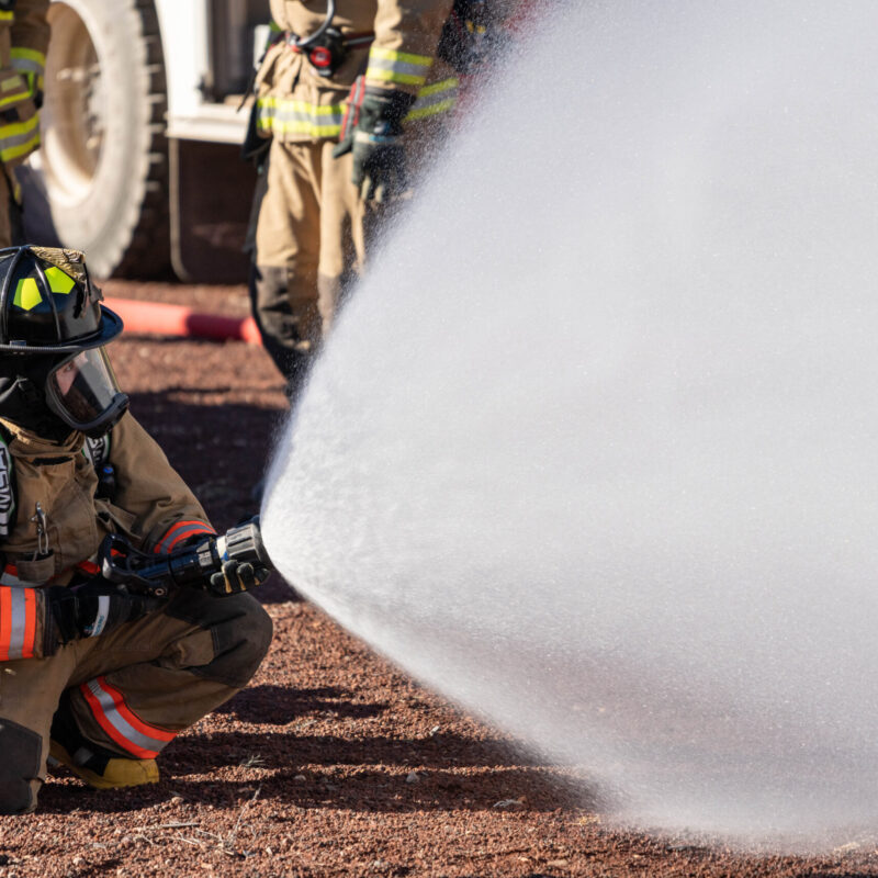 Vigile del fuoco in tenuta completa durante un addestramento con manichetta antincendio