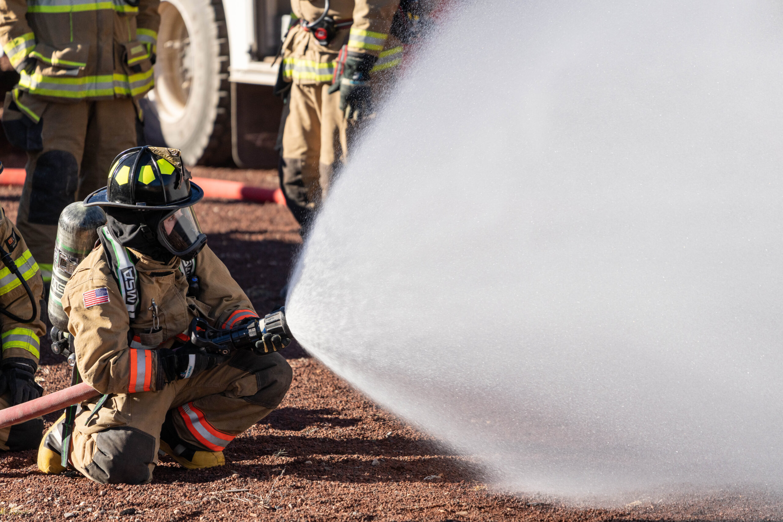 Vigile del fuoco in tenuta completa durante un addestramento con manichetta antincendio