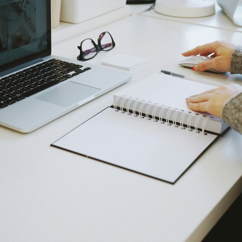Persona che lavora concentrata a una scrivania con laptop e taccuino