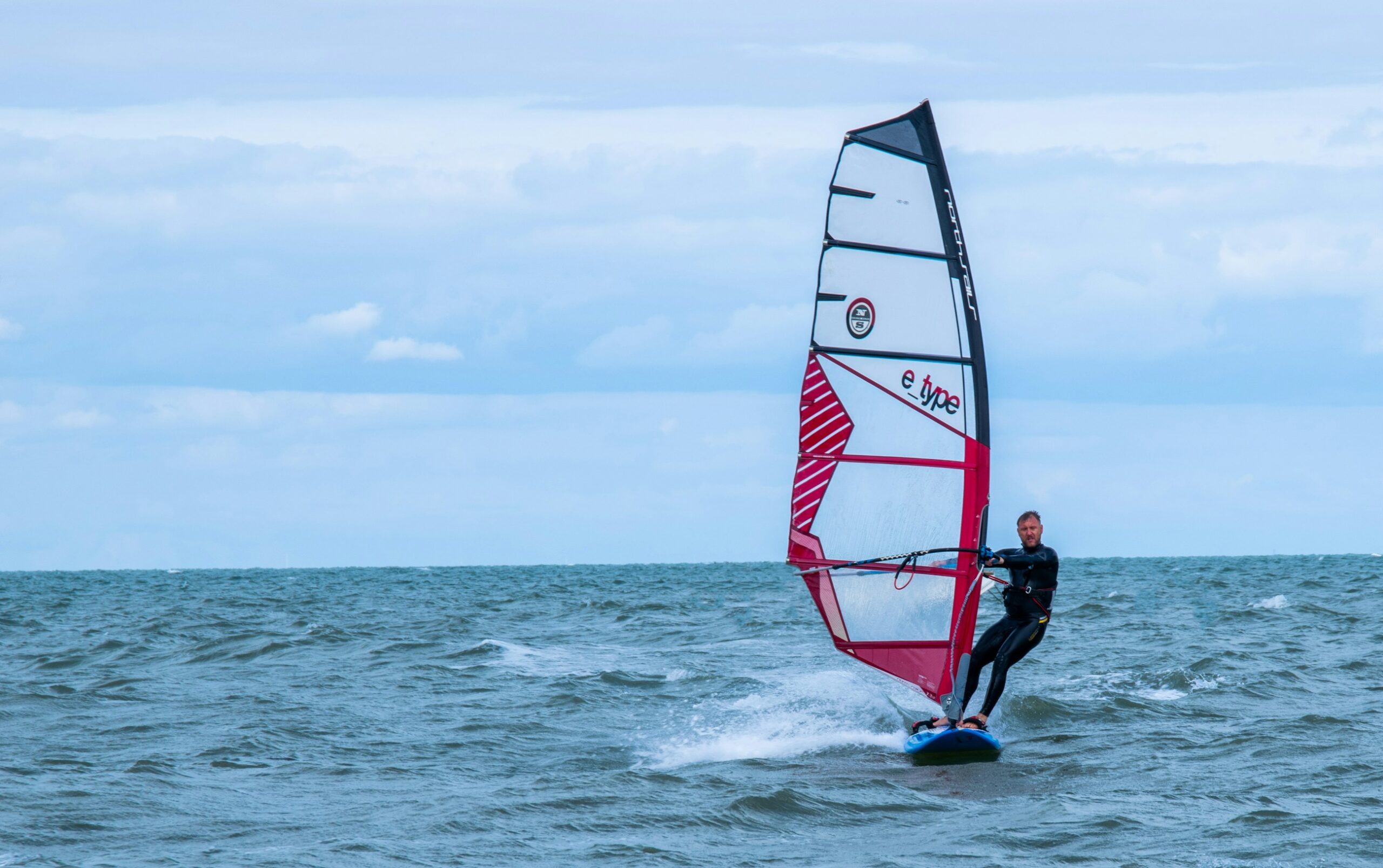 Persona che pratica windsurf in mare, ambientazione per lo sforzo cardiaco e visivo di questo sport acquatico