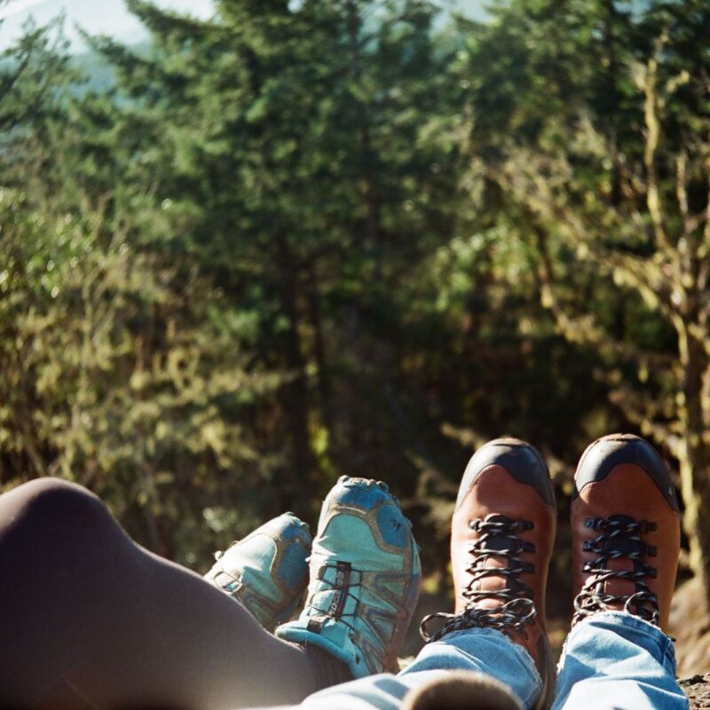 Gambe di due escursionisti a riposo in un bosco soleggiato, tema mobilita e articolazioni