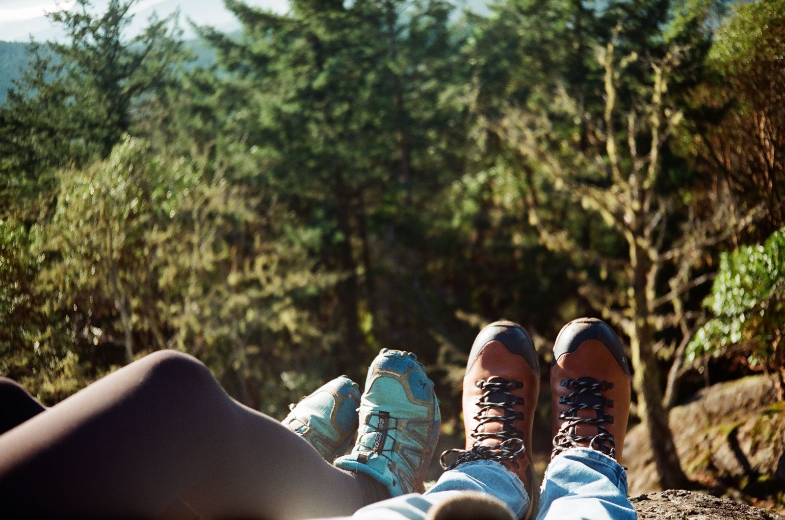 Gambe di due escursionisti a riposo in un bosco soleggiato, tema mobilita e articolazioni