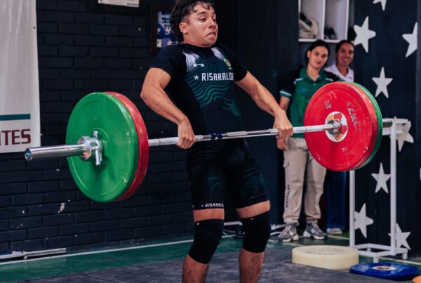 Giovane atleta che solleva pesi in palestra, allenamento di forza