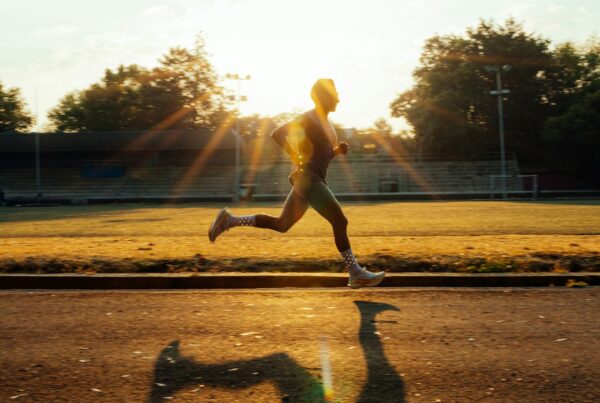 Corridore che si allena su una pista al tramonto, metabolismo energetico e L-carnitina