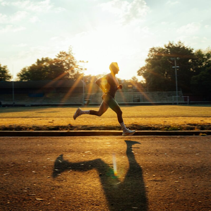 Corridore che si allena su una pista al tramonto, metabolismo energetico e L-carnitina