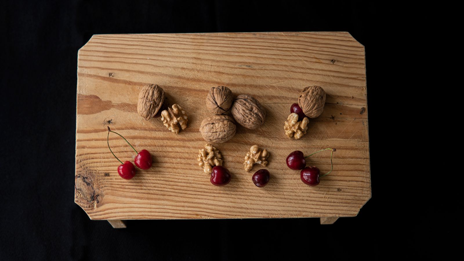 Ciliegie fresche e gherigli di noci su un tavolo di legno, alimenti tra le fonti naturali di melatonina