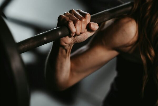 Atleta che solleva un bilanciere in palestra, allenamento di forza con integrazione di taurina e beta-alanina