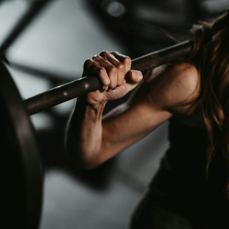 Atleta che solleva un bilanciere in palestra, allenamento di forza con integrazione di taurina e beta-alanina