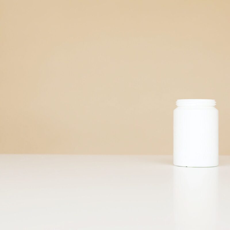 Flacone bianco neutro di integratore su fondo beige, immagine illustrativa del tempo di utilizzo