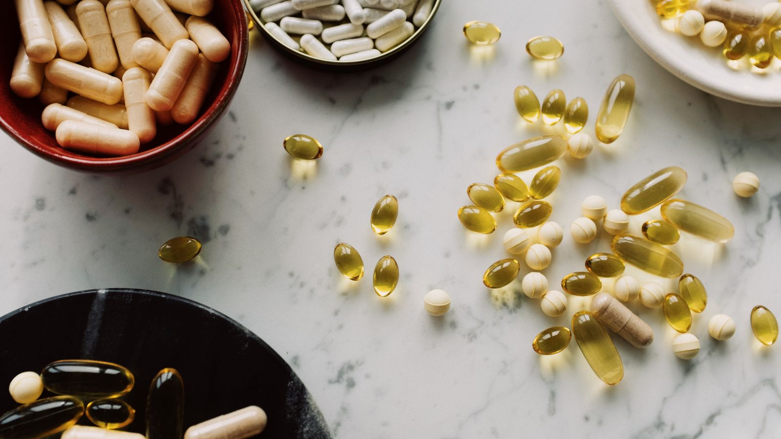 Capsule e integratori diversi disposti su un piano in marmo, immagine illustrativa di formule con più ingredienti