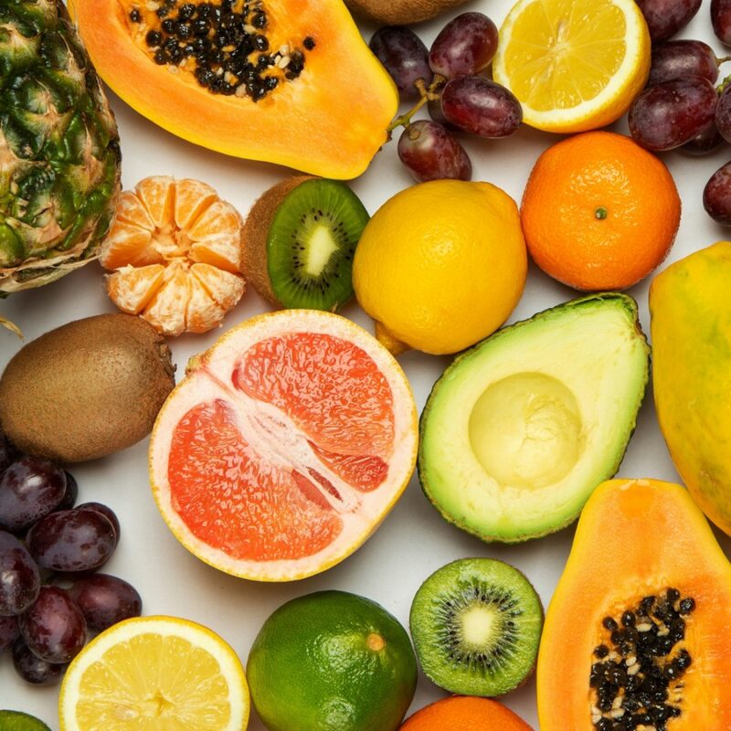 Assortimento di frutta fresca disposto su fondo chiaro, esempio di varietà alimentare
