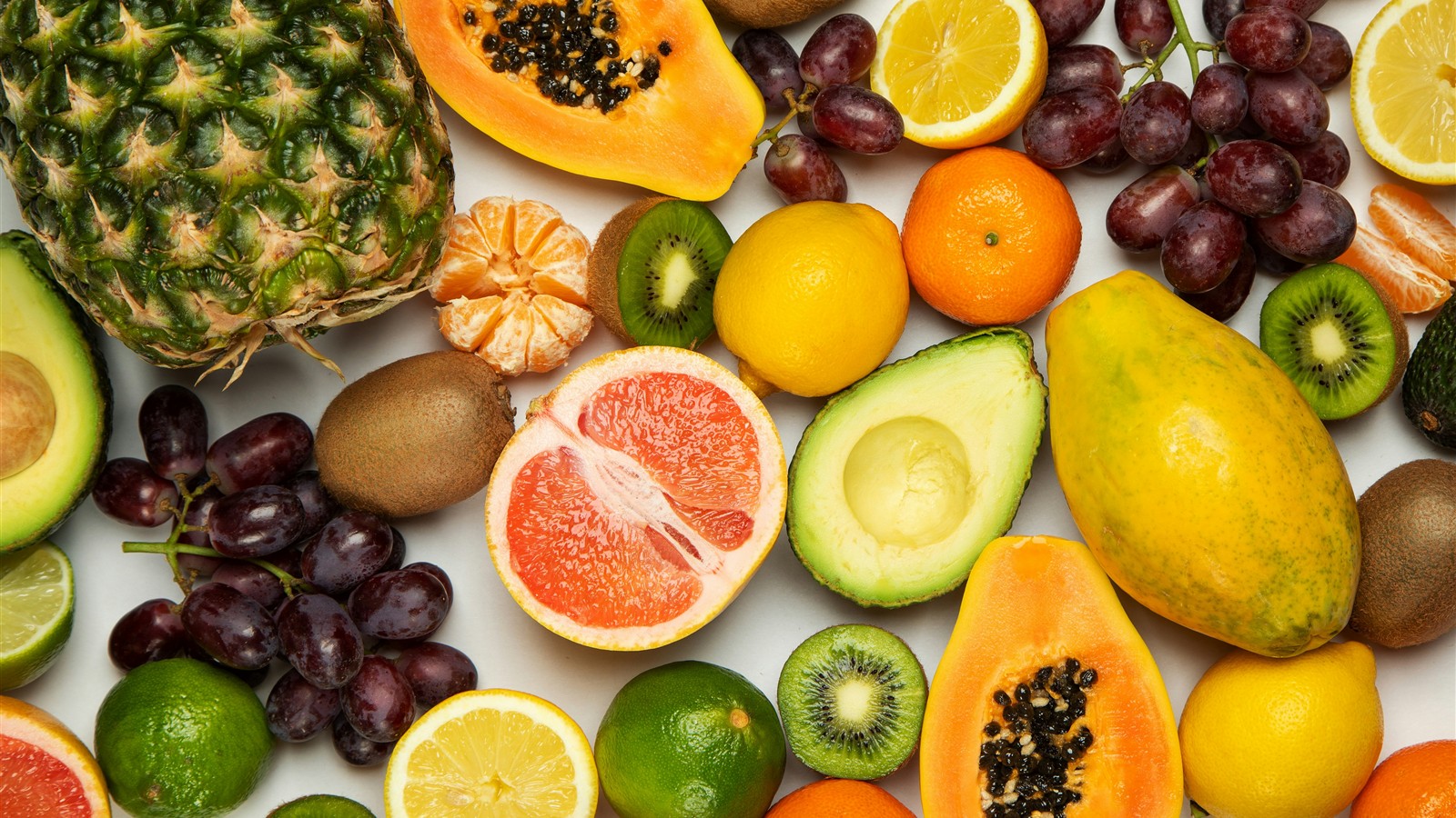 Assortimento di frutta fresca disposto su fondo chiaro, esempio di varietà alimentare