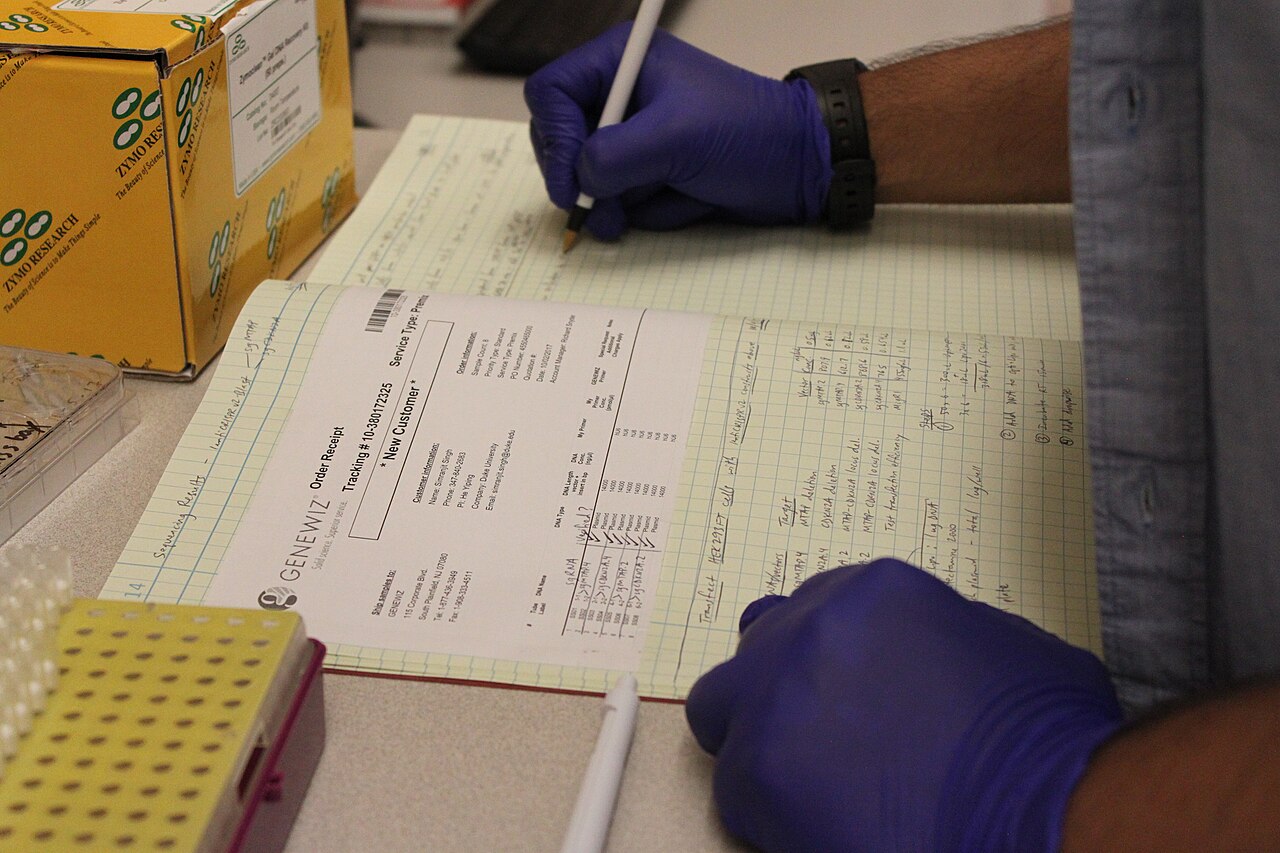 Persona in laboratorio che annota osservazioni su un quaderno scientifico