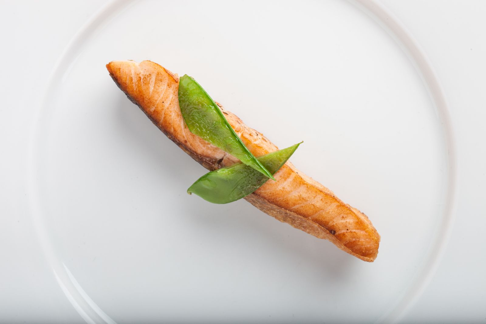 Filetto di salmone cotto con guarnizione verde su un piatto bianco, alimento che contiene omega-3